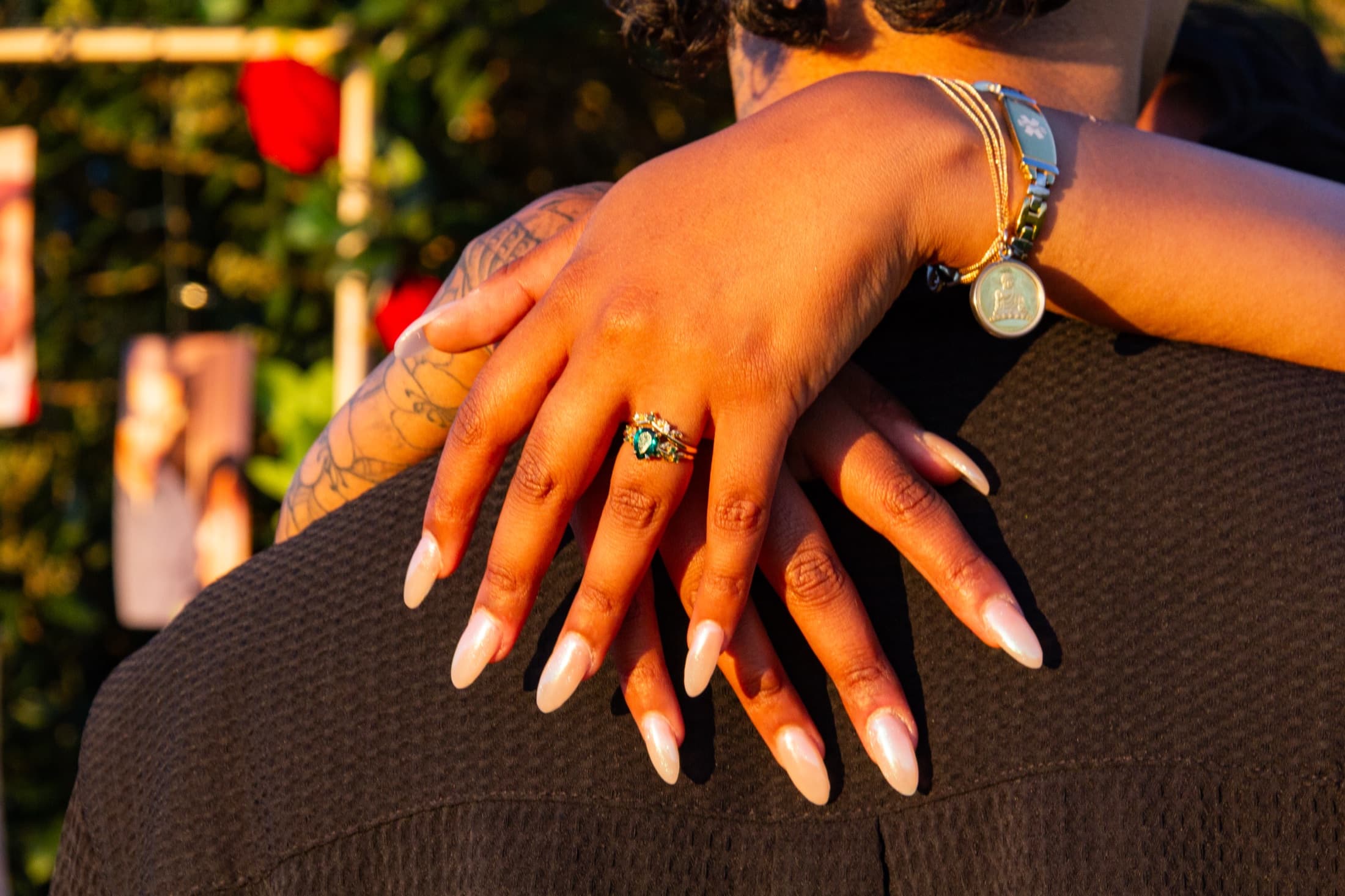 Robyn's hands crossed over Dash's shoulder, her emerald and gold engagement ring catching the golden light
