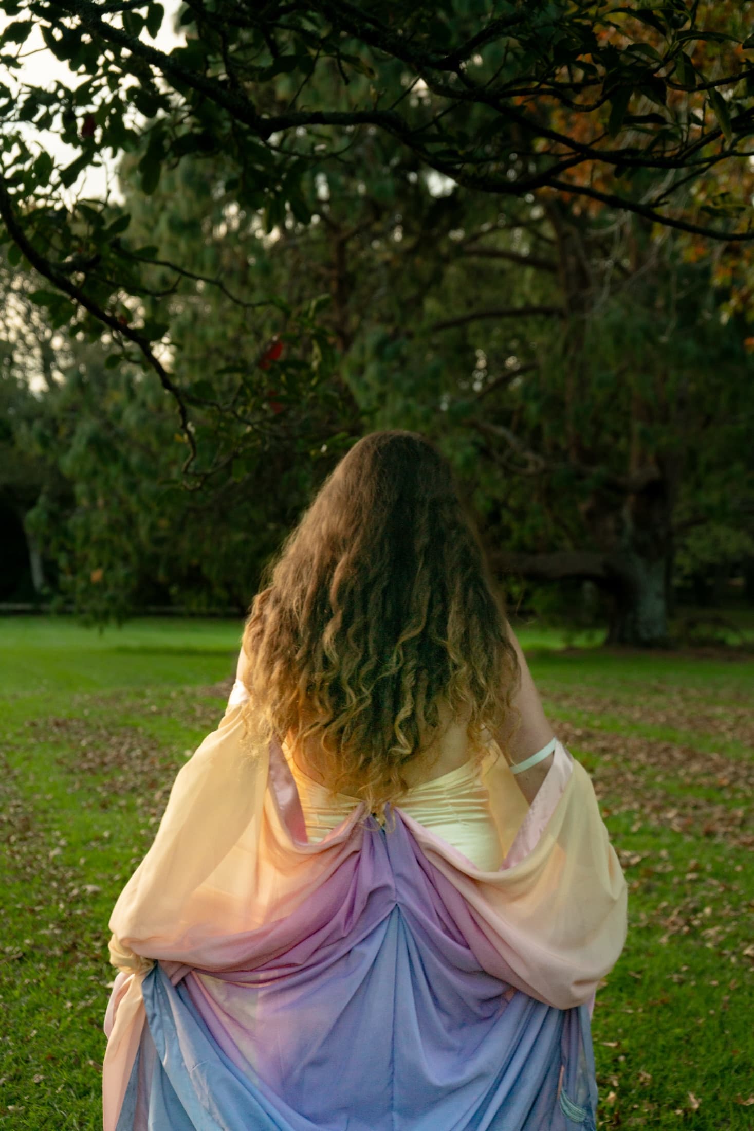 Model mid-spin, gown flaring across the grass in low evening light